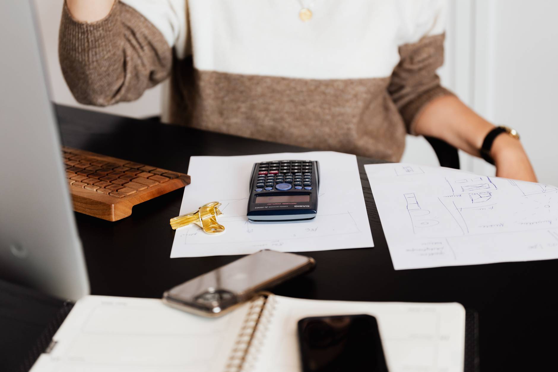 crop woman using calculator while counting bills in workspace