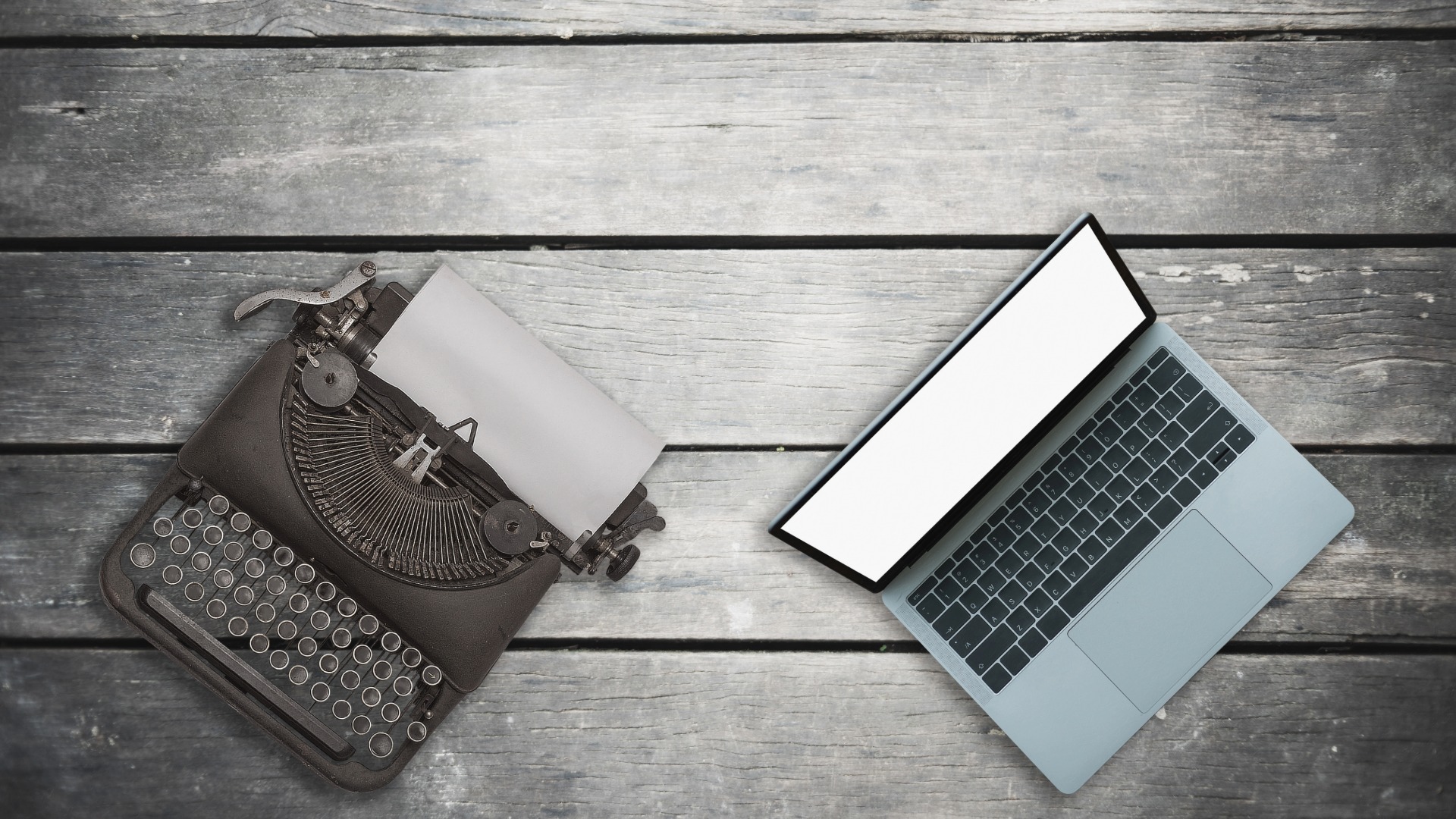 old fashioned type writer next to a laptop on a wooden table