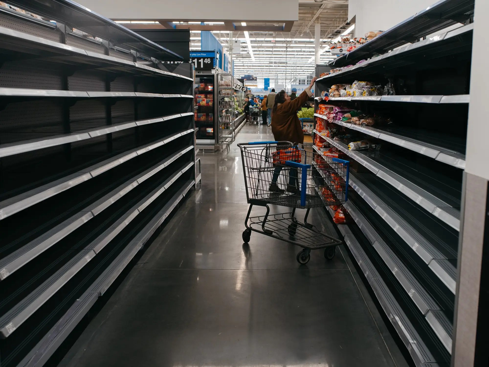 Woman picking through what remains in a grocery store in preparation for Winter Storm Fern.