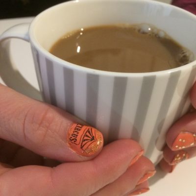 kädet kahvikupin ympärillä, peukalon kynnessä sirkusteltta