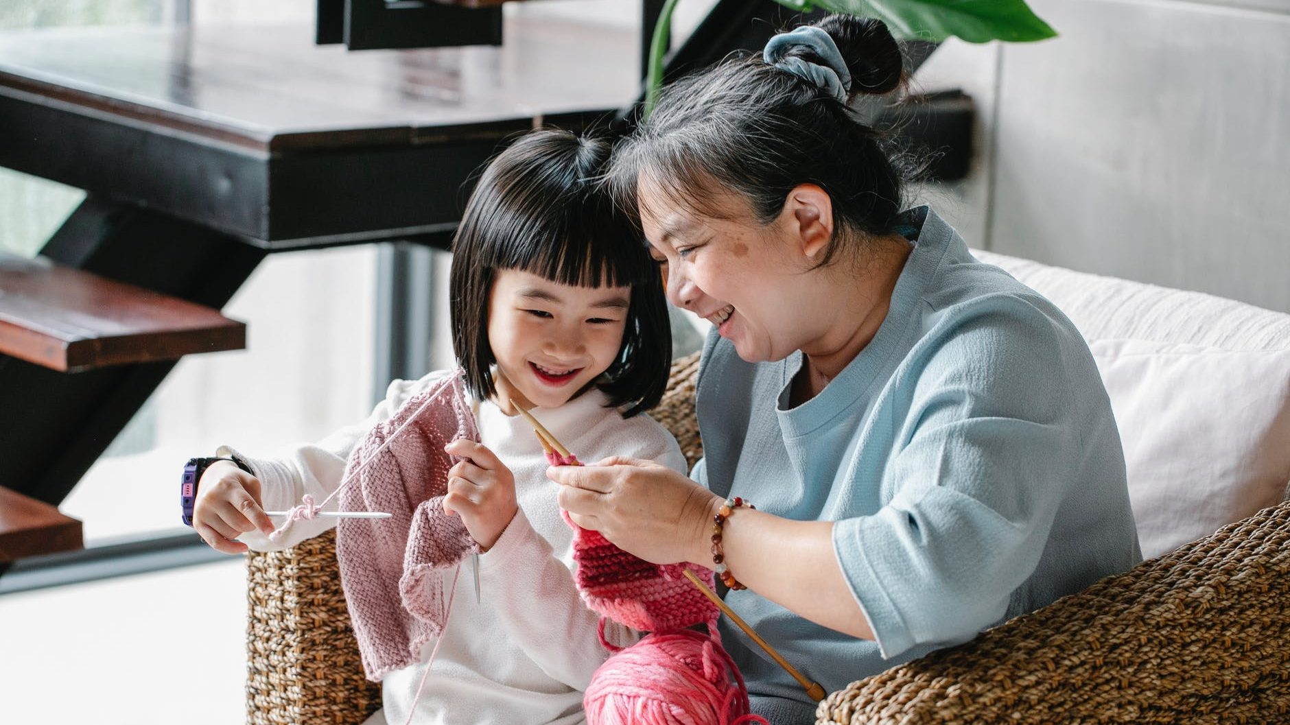 smiling ethnic kid knitting with grandmother during weekend at home