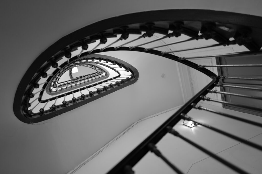 A monochrome image looking upward through a staircase.