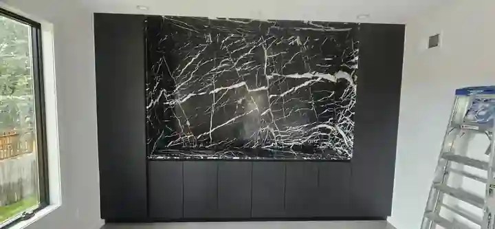 Custom black marble feature wall and built-in woodworking by Socho Sons LLC