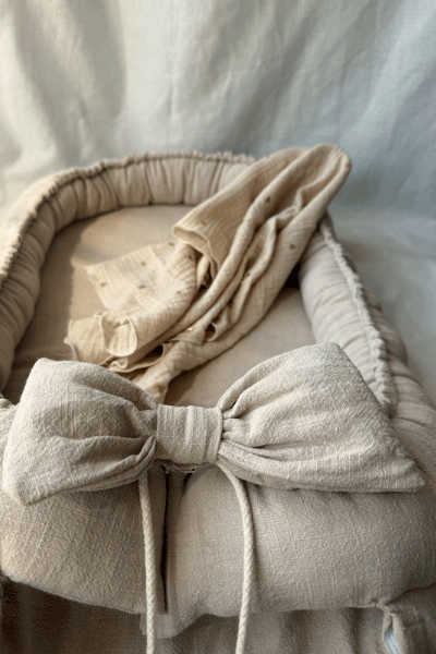 Beige babynest i lin och bomull med avtagbar rosett