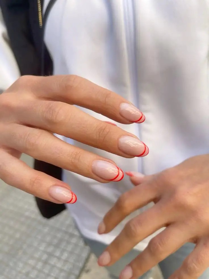 Short nude nails with thin red French tip outlines.