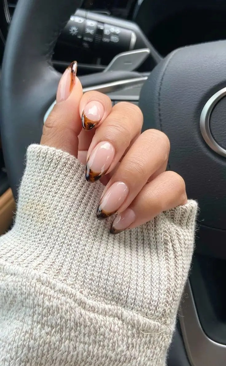 Almond nude nails with brown tortoise-shell French tips and a glossy finish.