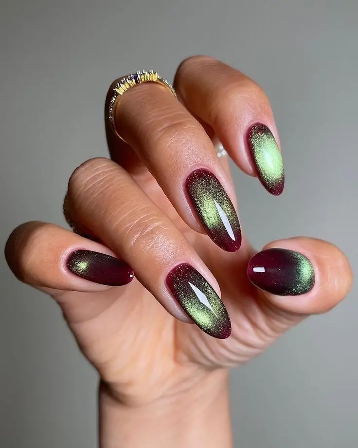 Burgundy almond nails with a magnetic emerald green cat eye effect.
