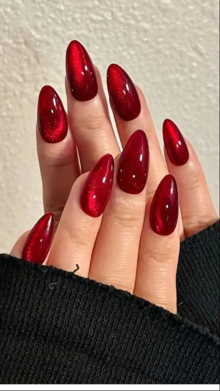 Glossy deep red almond nails with a rich ruby cat eye shimmer.