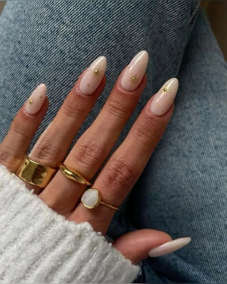 White-to-nude gradient nails featuring small gold star decals.