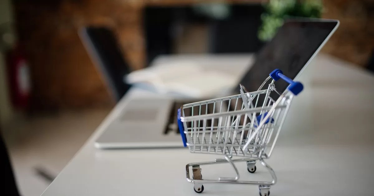 Mini shopping cart placed on a table next to a laptop in a modern office setting