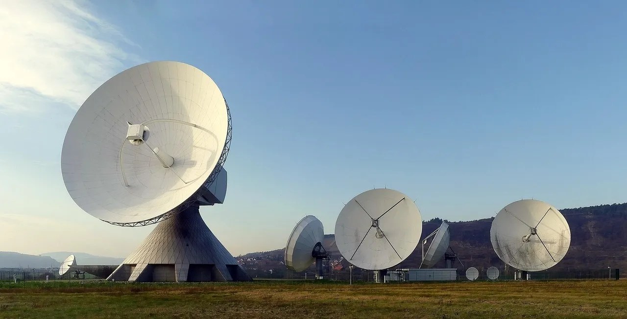 Large satellite dish antennas in an open field under a clear sky