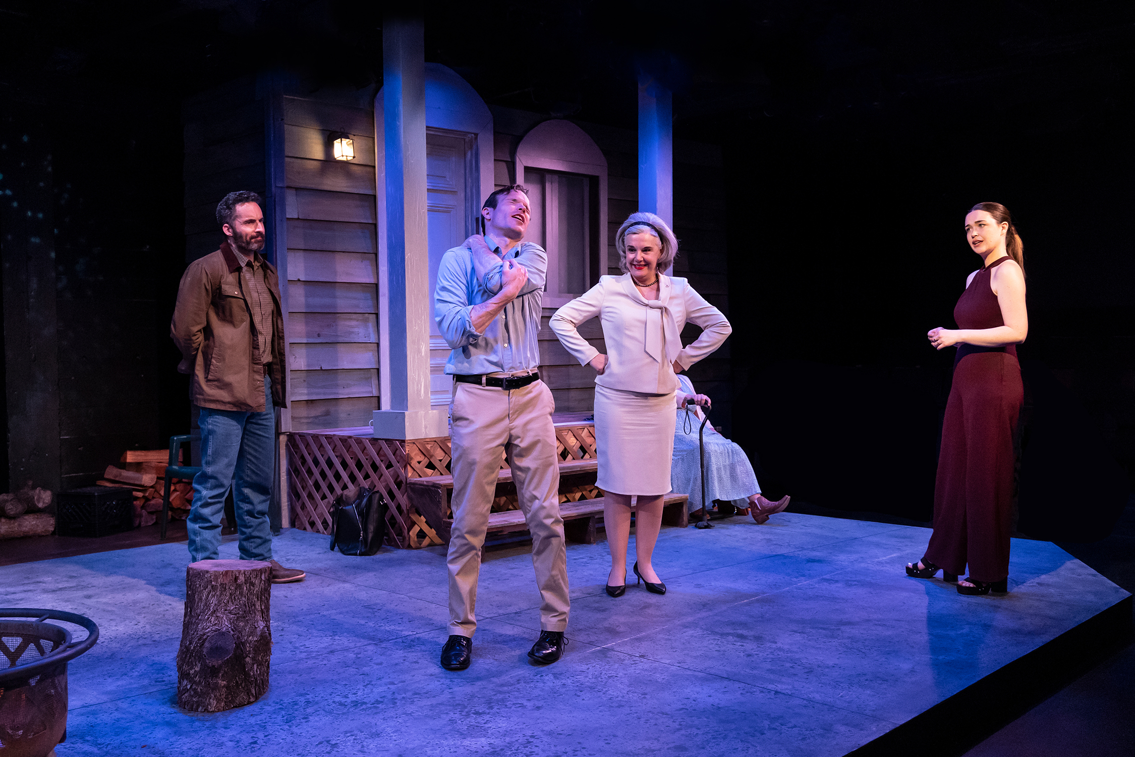 Four theater actors stand onstage, with one man grabbing the back of his neck.