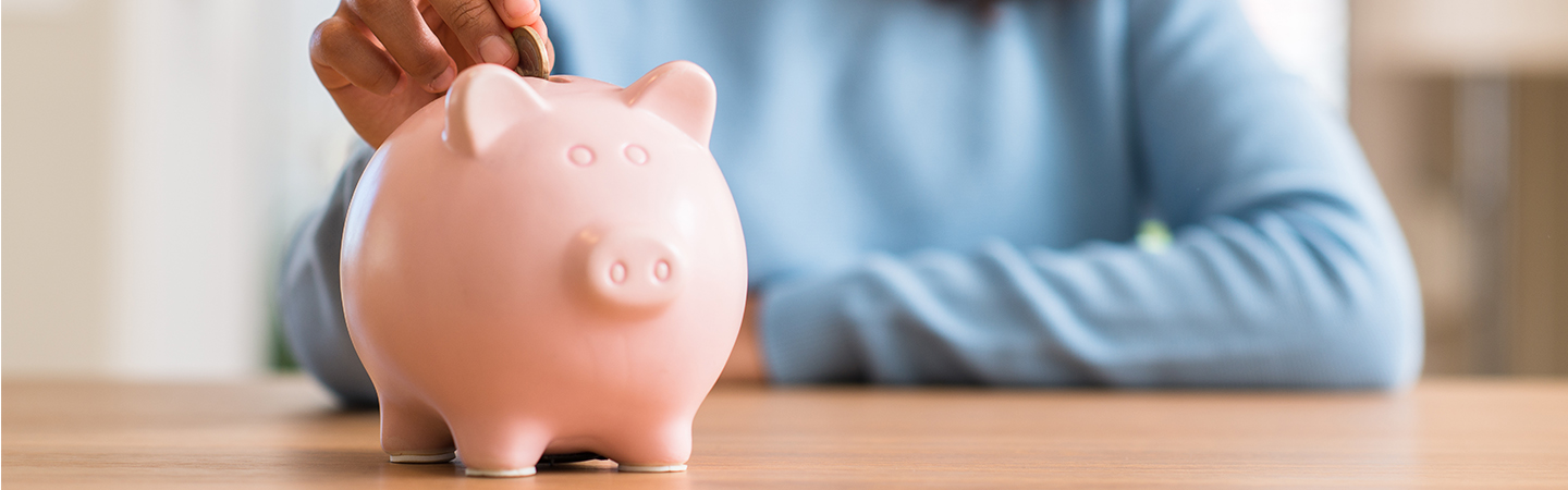A person putting a coin into a piggy bank.