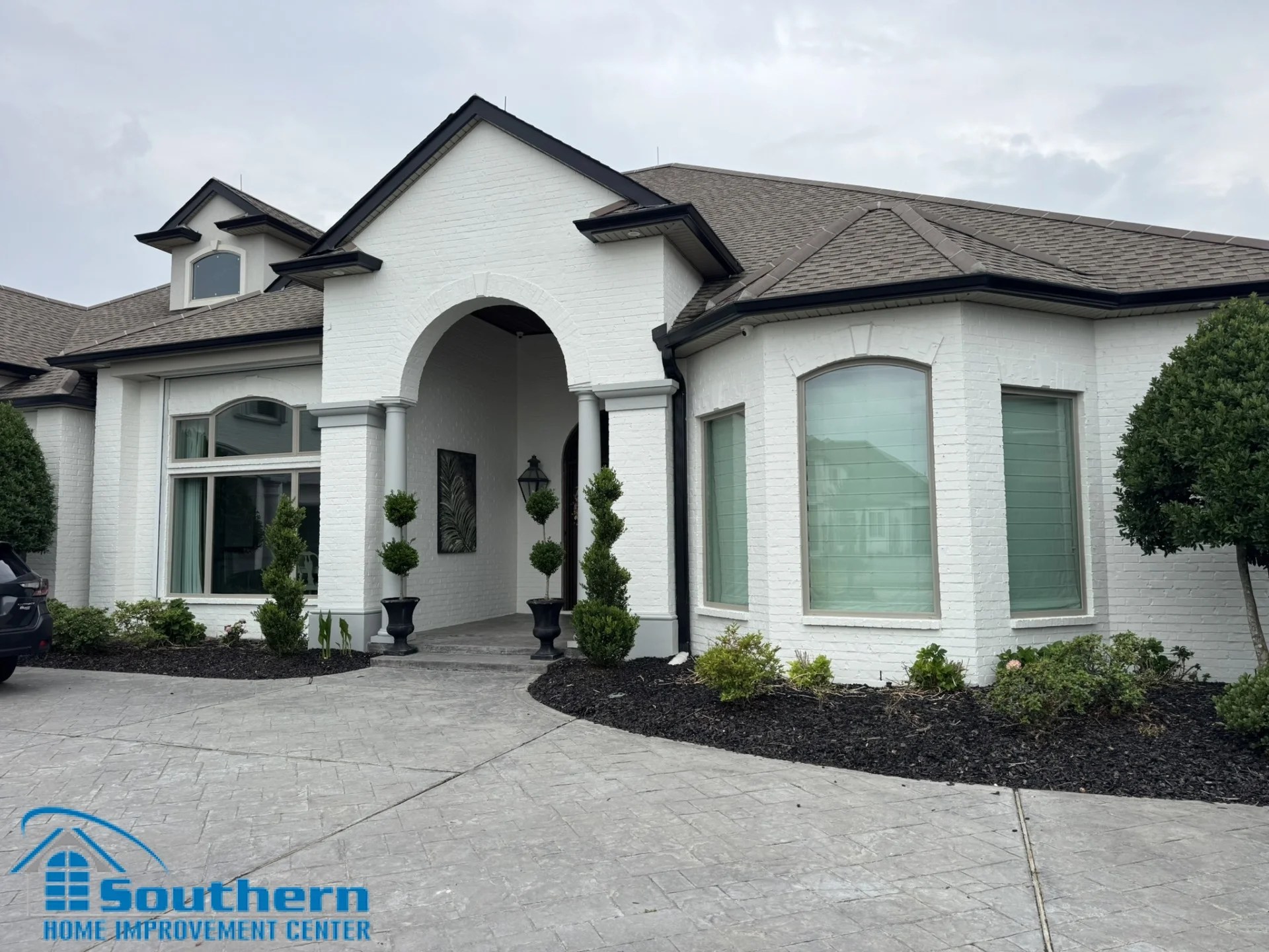 Full exterior view of a white brick Slidell home after custom TectView vinyl window installation with Fossil frames