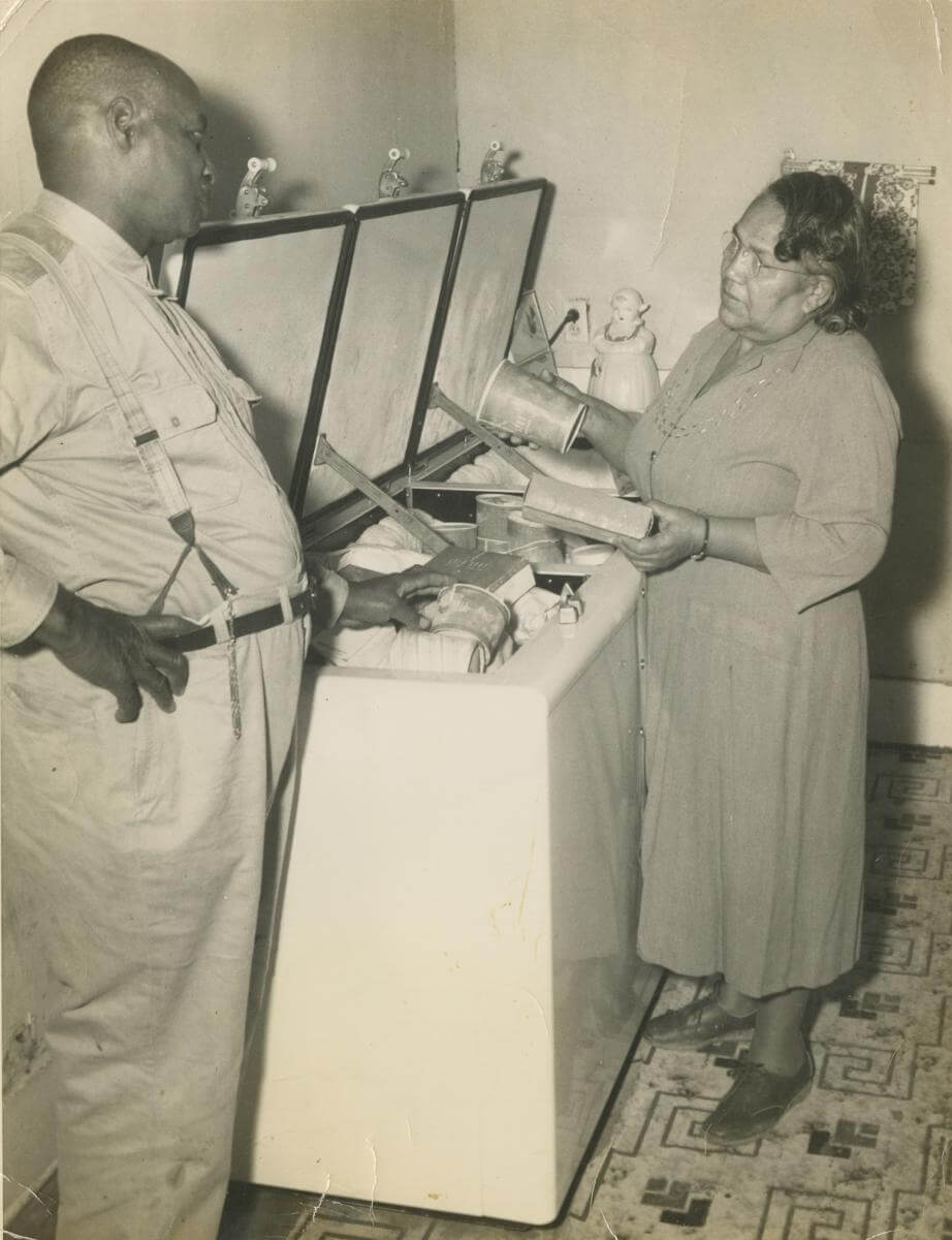 Edward Scott Sr. and Juanita Scott at the freezer, Scott farm, Leflore County, Mississippi, ca. 1950s. Photograph by unknown creator. Originally published in Julian Rankin's Catfish Dream: Ed Scott's Fight for His Family Farm and Racial Justice in the Mississippi Delta (University of Georgia Press, 2018). Courtesy of Willena Scott-White. A sepia-toned photograph showing Edward Scott Sr. and Juanita Scott standing at a freezer