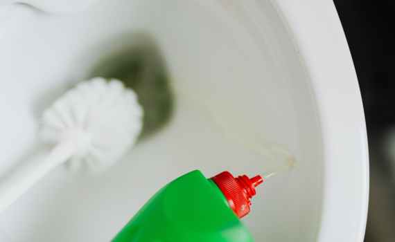 liquid toilet cleaner pouring in toilet bowl