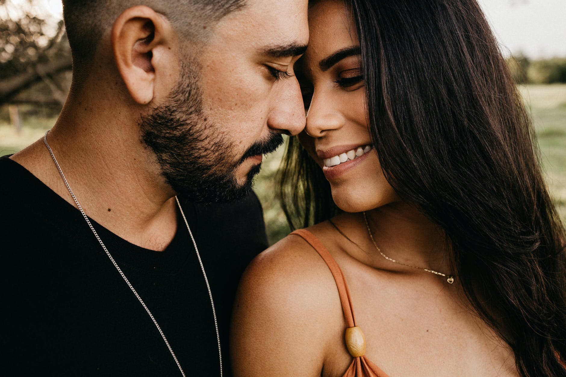 crop hispanic couple touching noses in countryside field