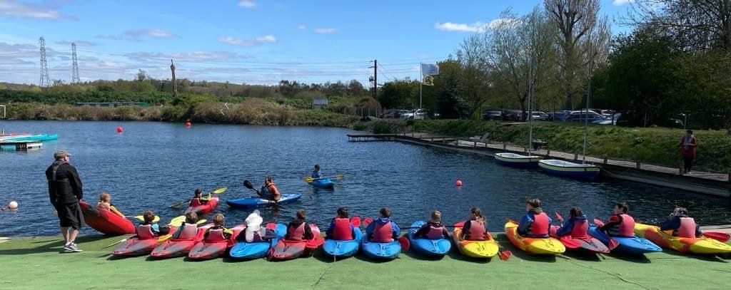 children sitting in line of canoes