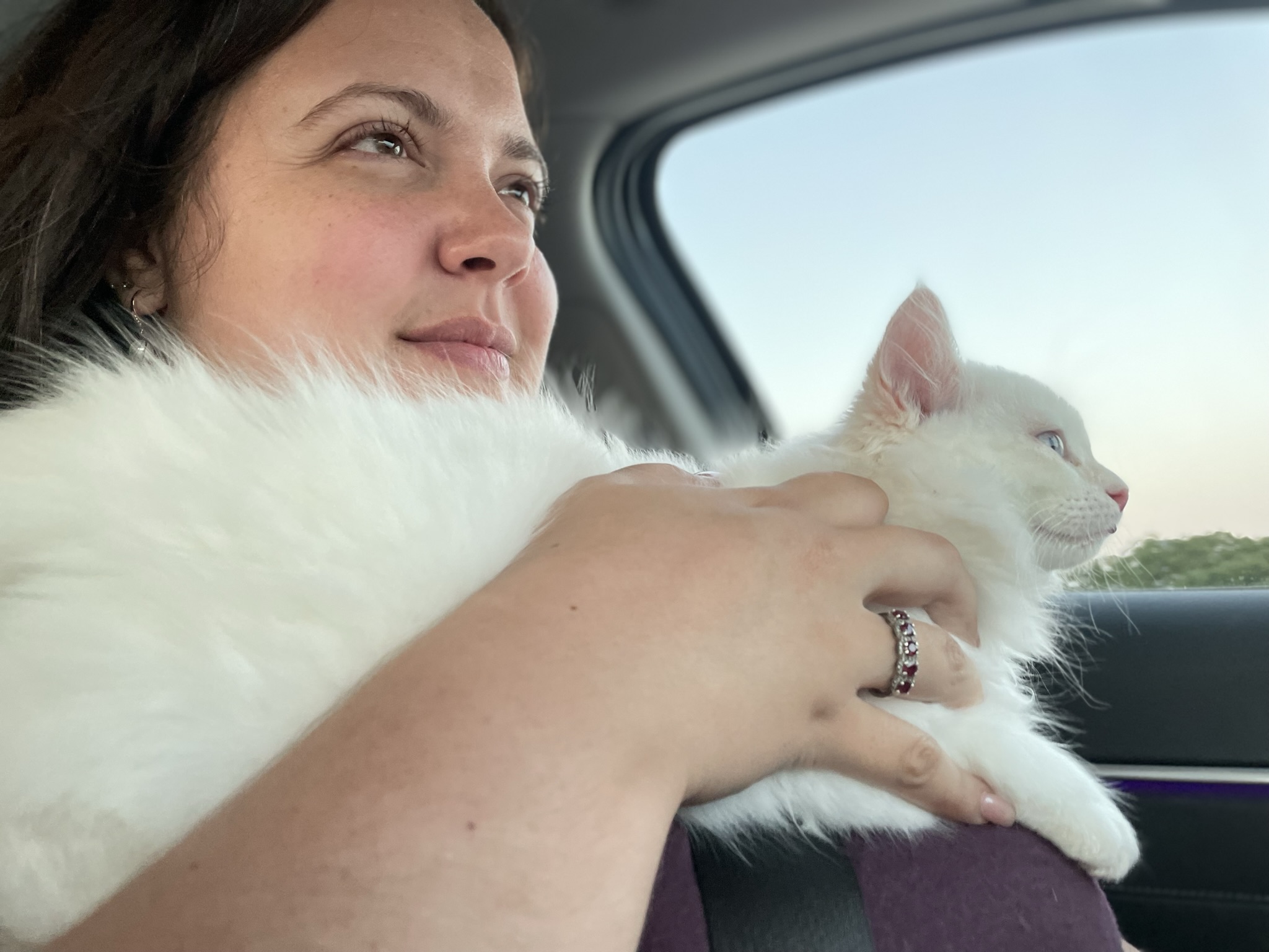 Shaddiah holding her cat with a peaceful smile during a car ride