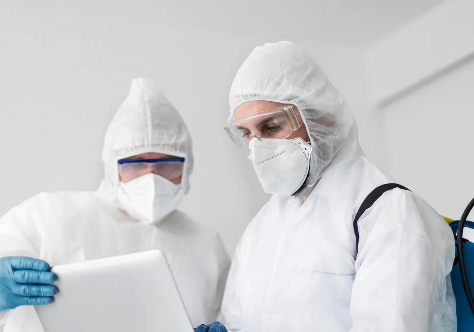 Técnicos con traje de protección y equipo de sanitización