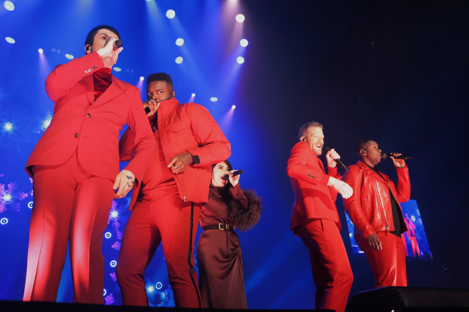 members of Pentatonix preform on stage in red suits