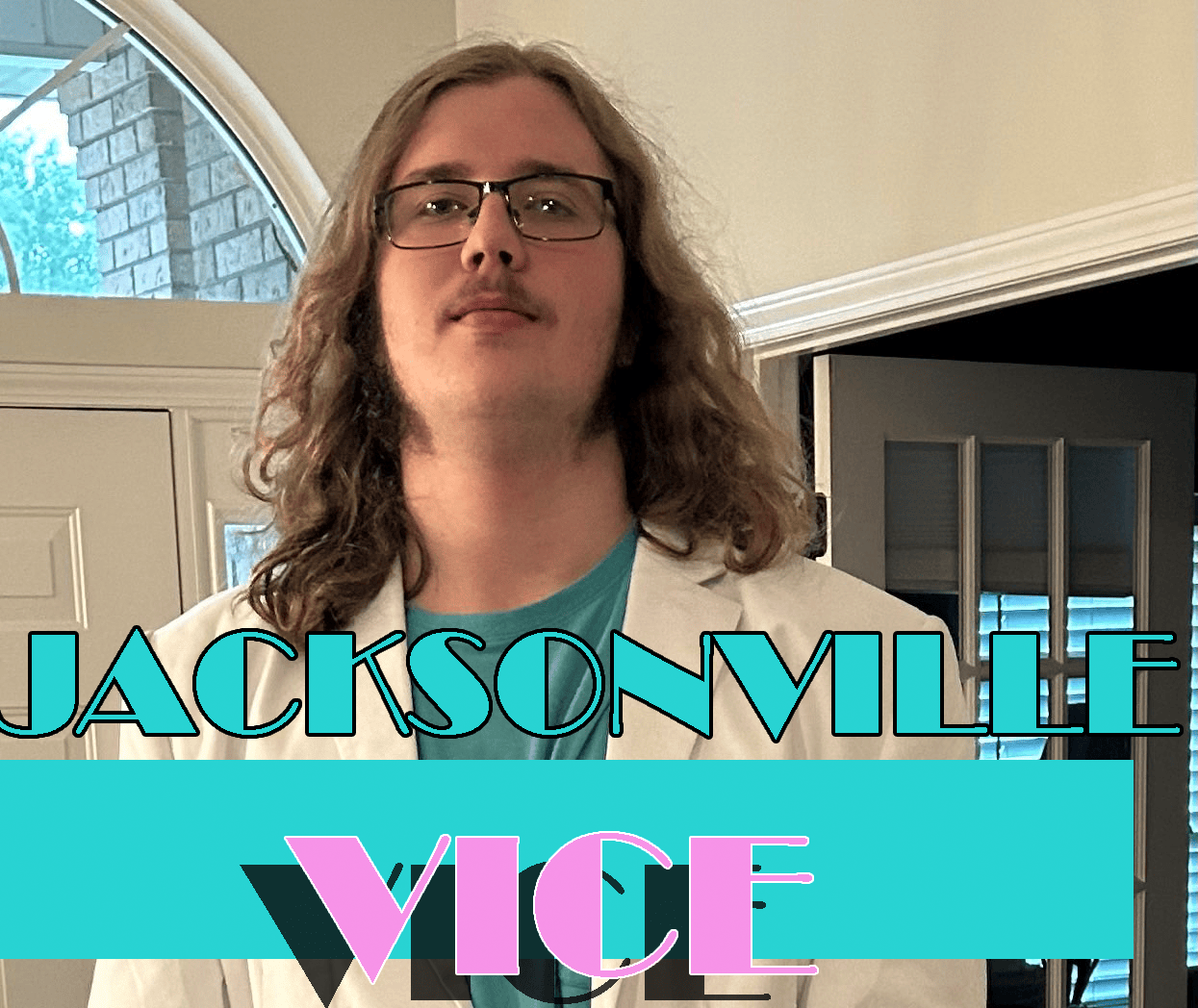 young man with long hair, glasses and wearing a white blazer with the words Jacksonville Vice