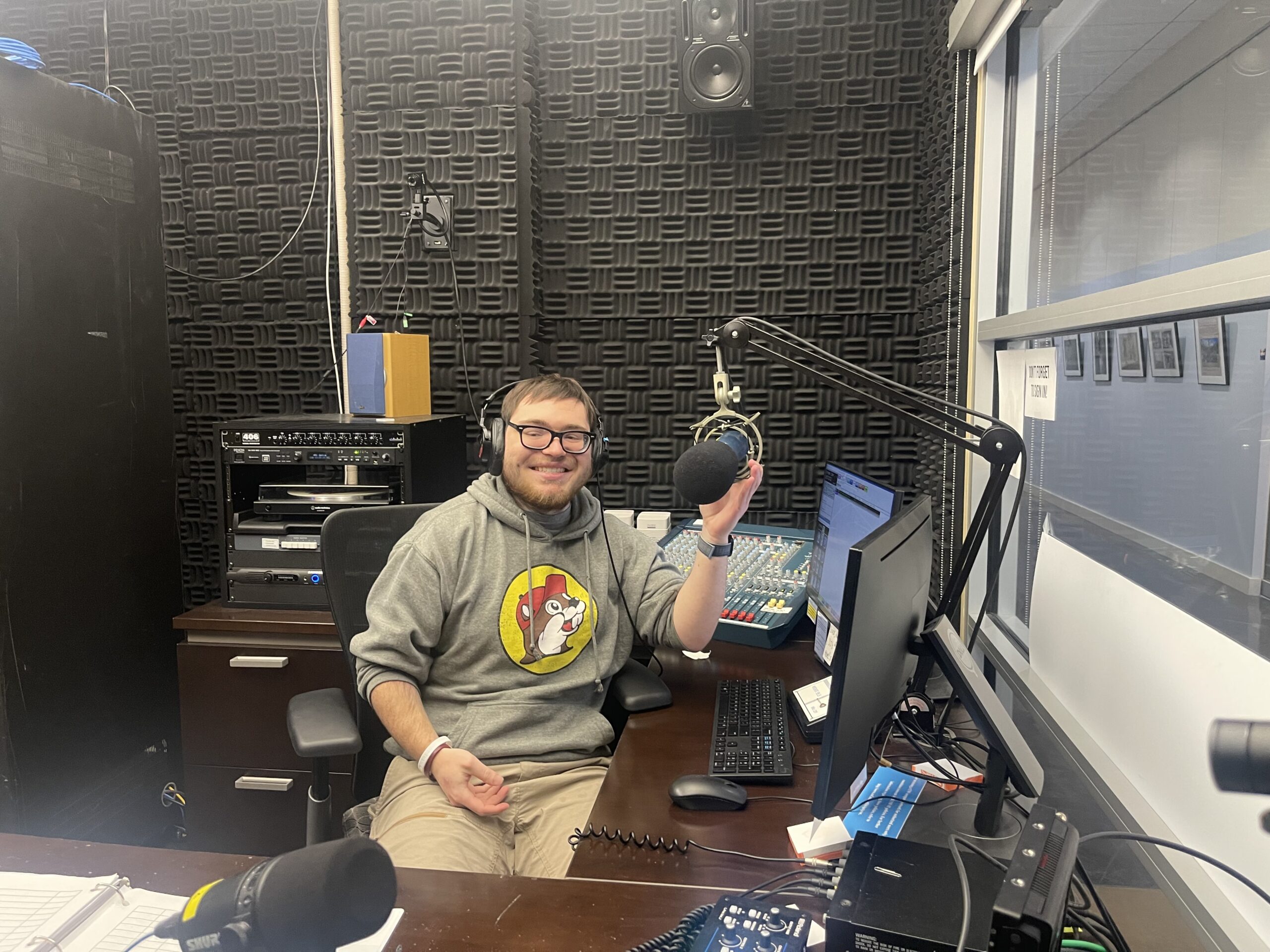 DJ Trey, wearing a grey sweatshirt, and sitting in the DJ booth
