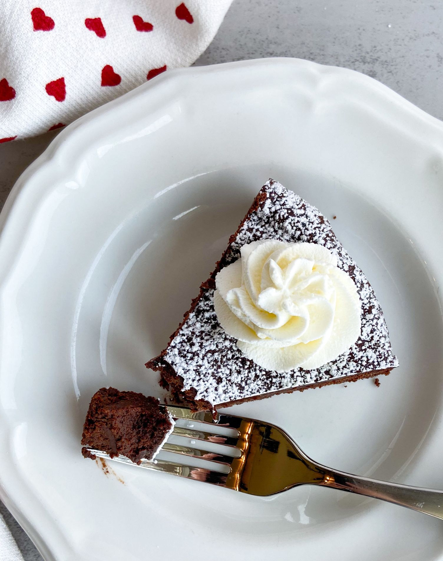 Chocolate cake on a plate with a bite on a fork.