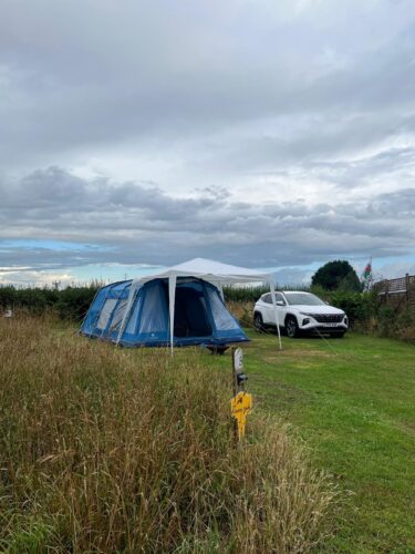 A tent sent up including 1 car on a fully serviced grass pitch