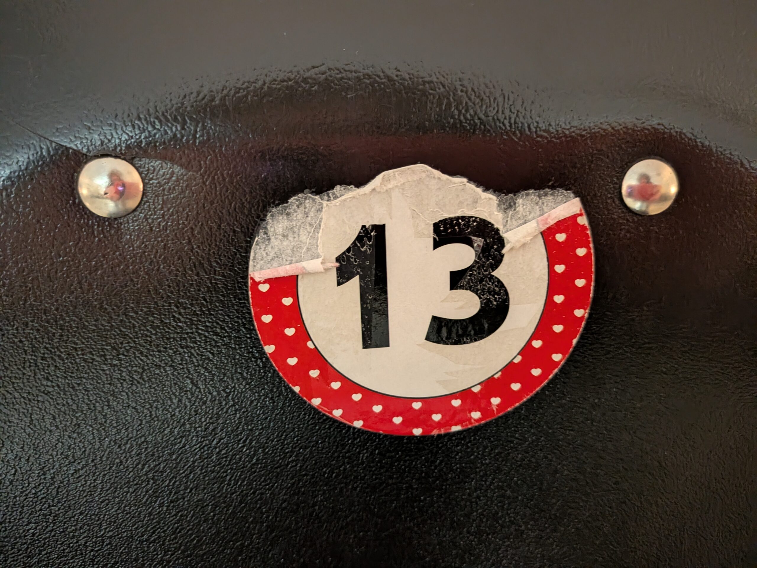 A torn number 13 sticker stuck on the back of a seat.