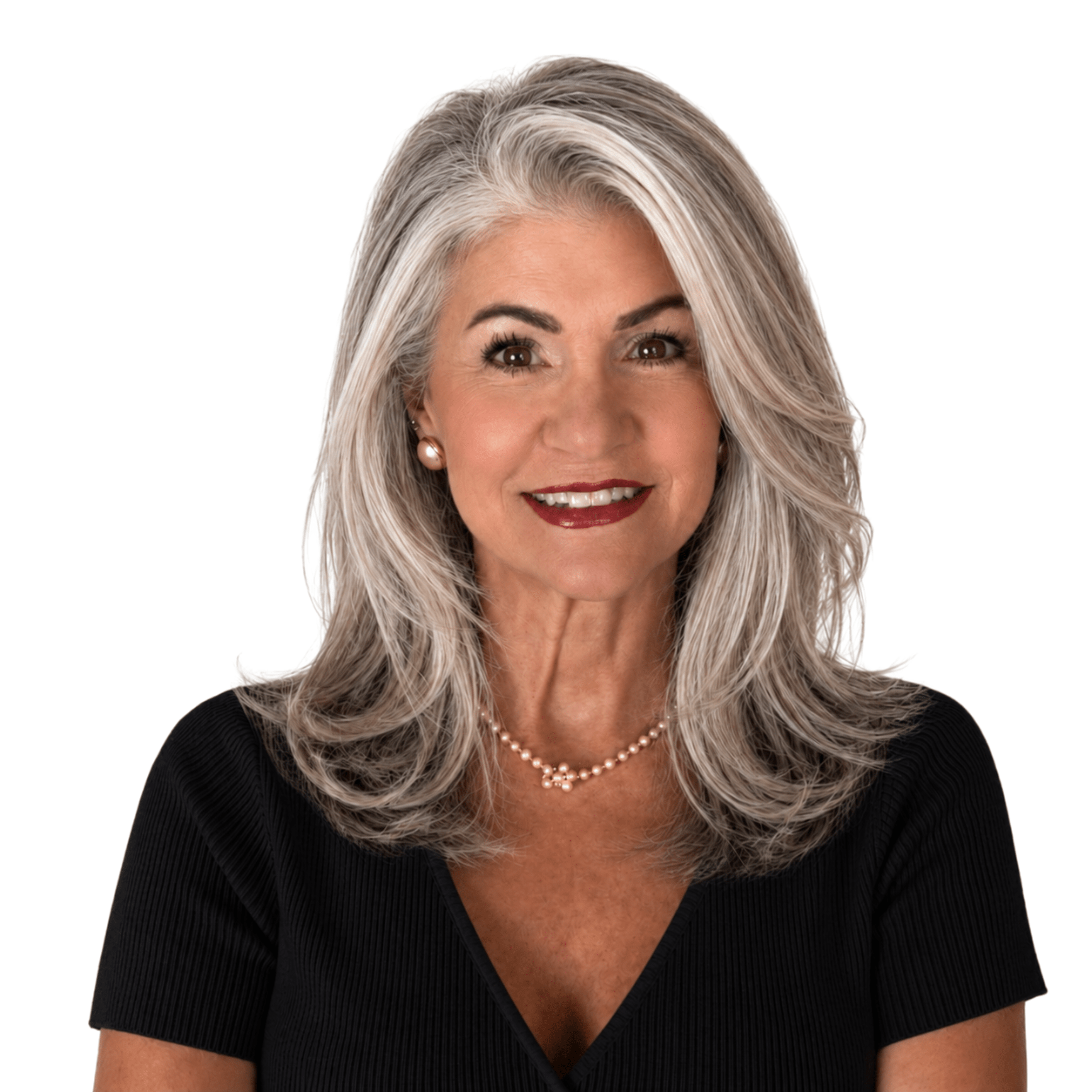 Smiling woman with silver-grey hair wearing a pearl necklace and pearl earrings, in a black V-neck top against a white background.