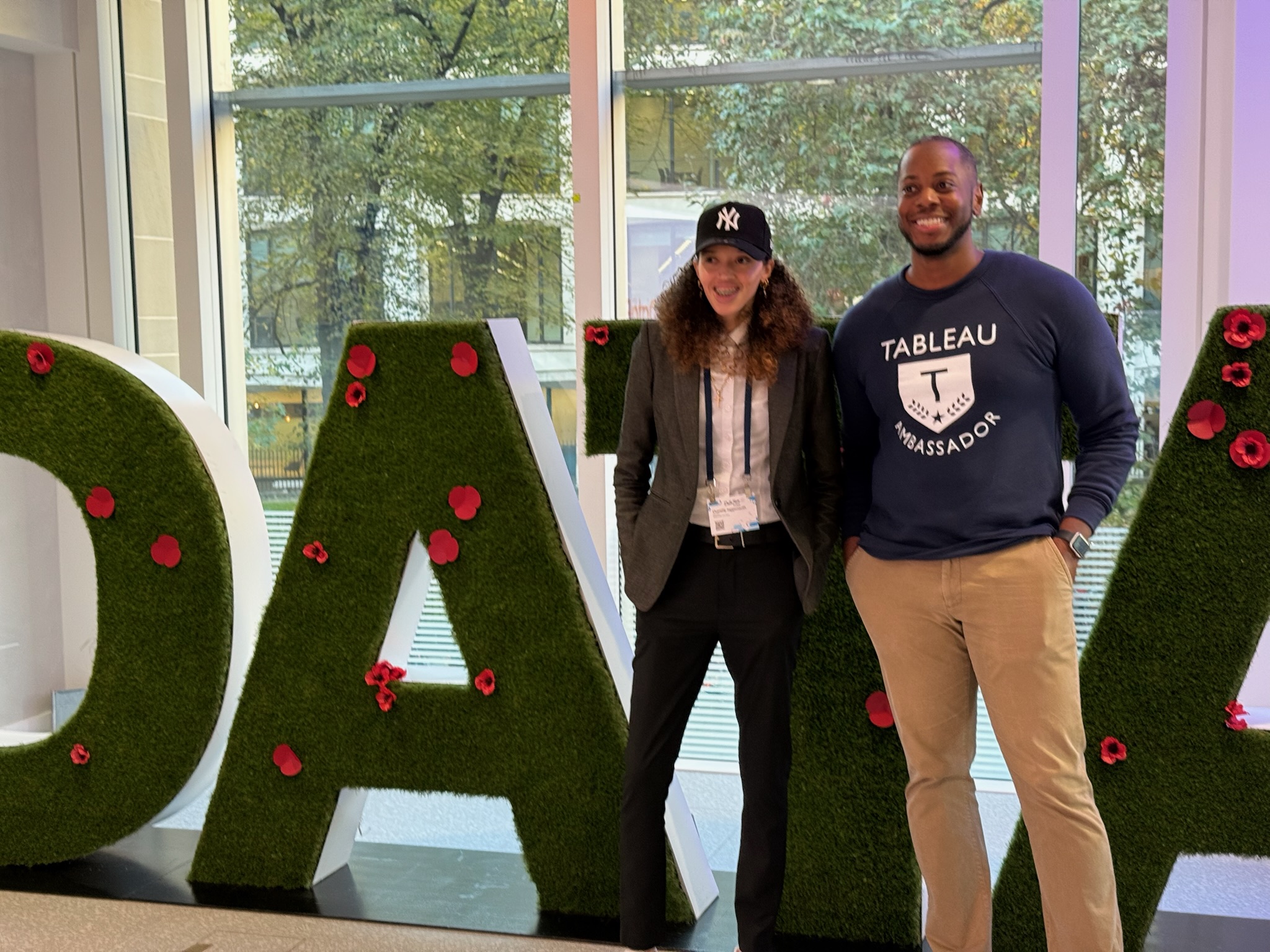 Sekou Tyler and a colleague standing in front of oversized grass-covered DATA letters decorated with red flowers