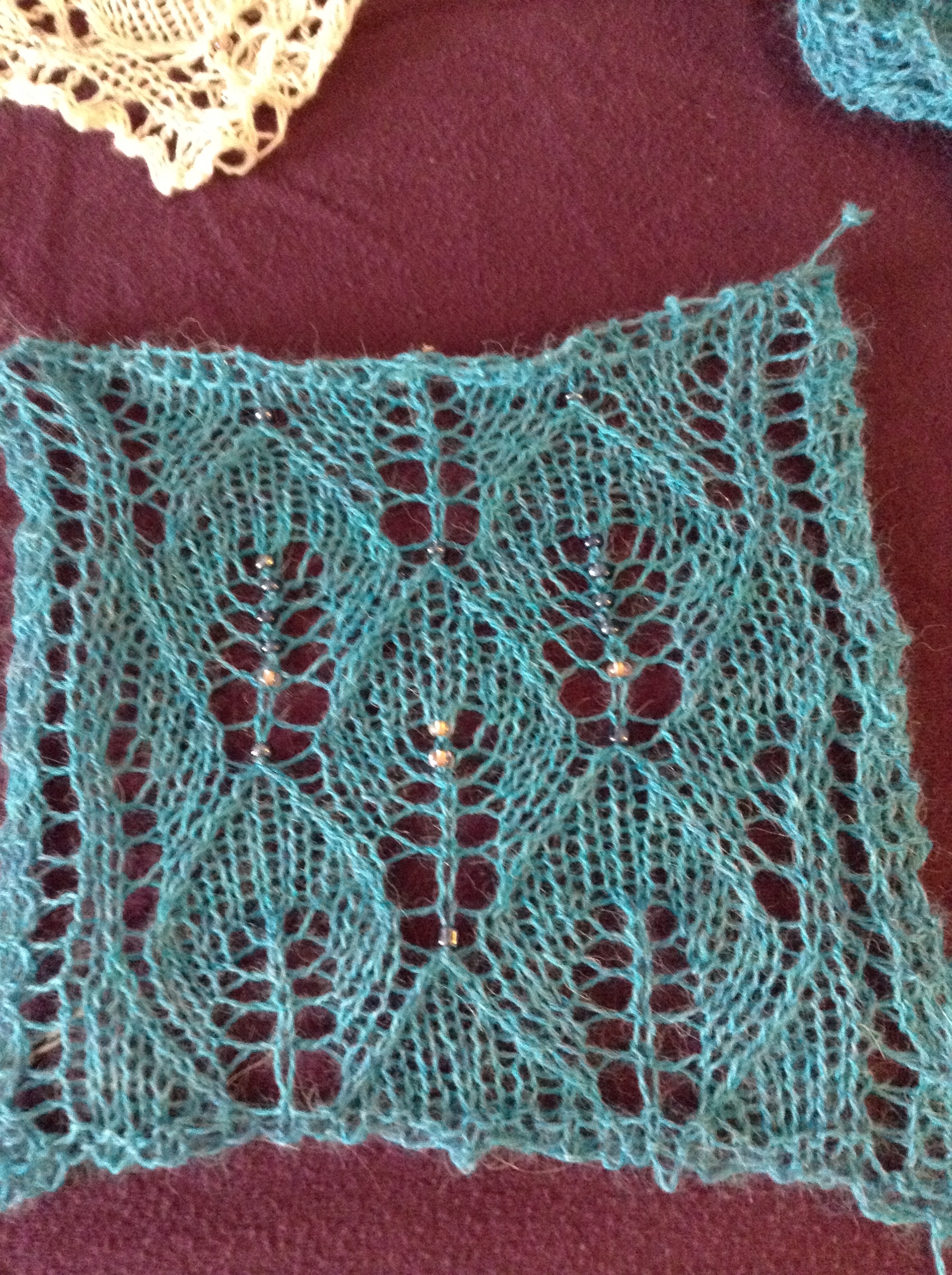 A small blocked swatch of the turquoise shawl, with several "test" beads. I settled on the dark, metallic blue.