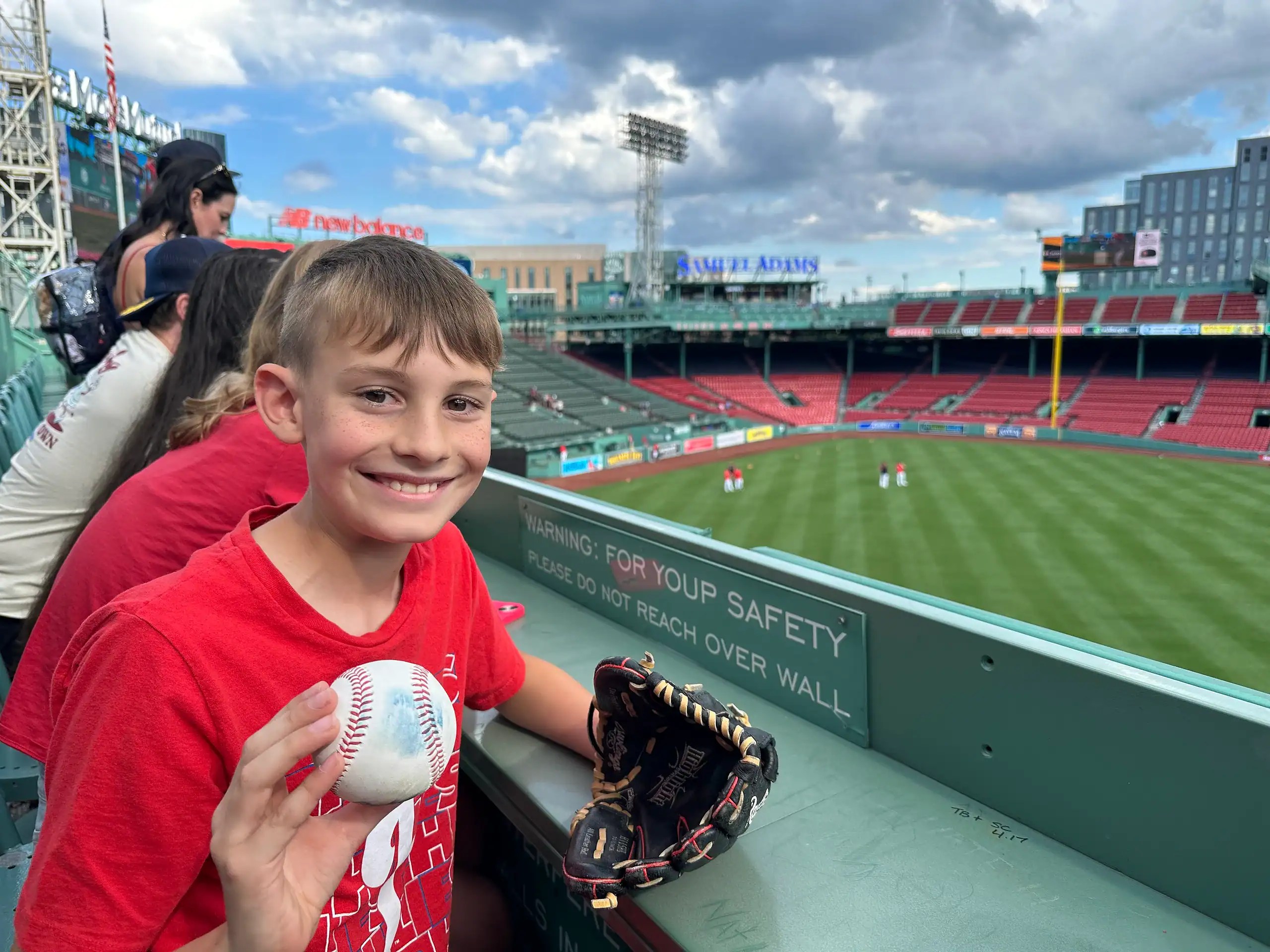boy holding baseball caught during Fenway Park tour on the Green Monster