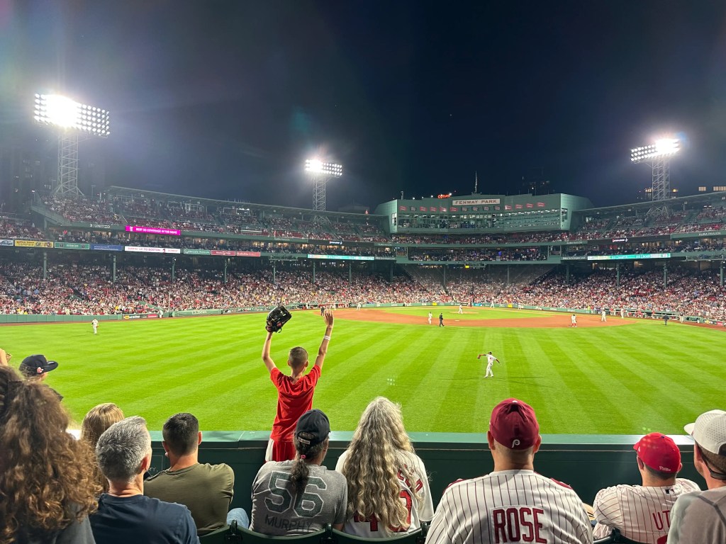 Fan cheering in a crowded baseball stadium during a night game