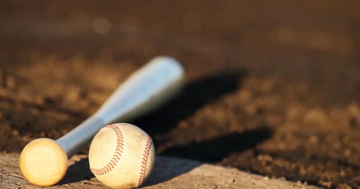 Baseball bat and ball on a field representing a Cooperstown packing list for players and parents