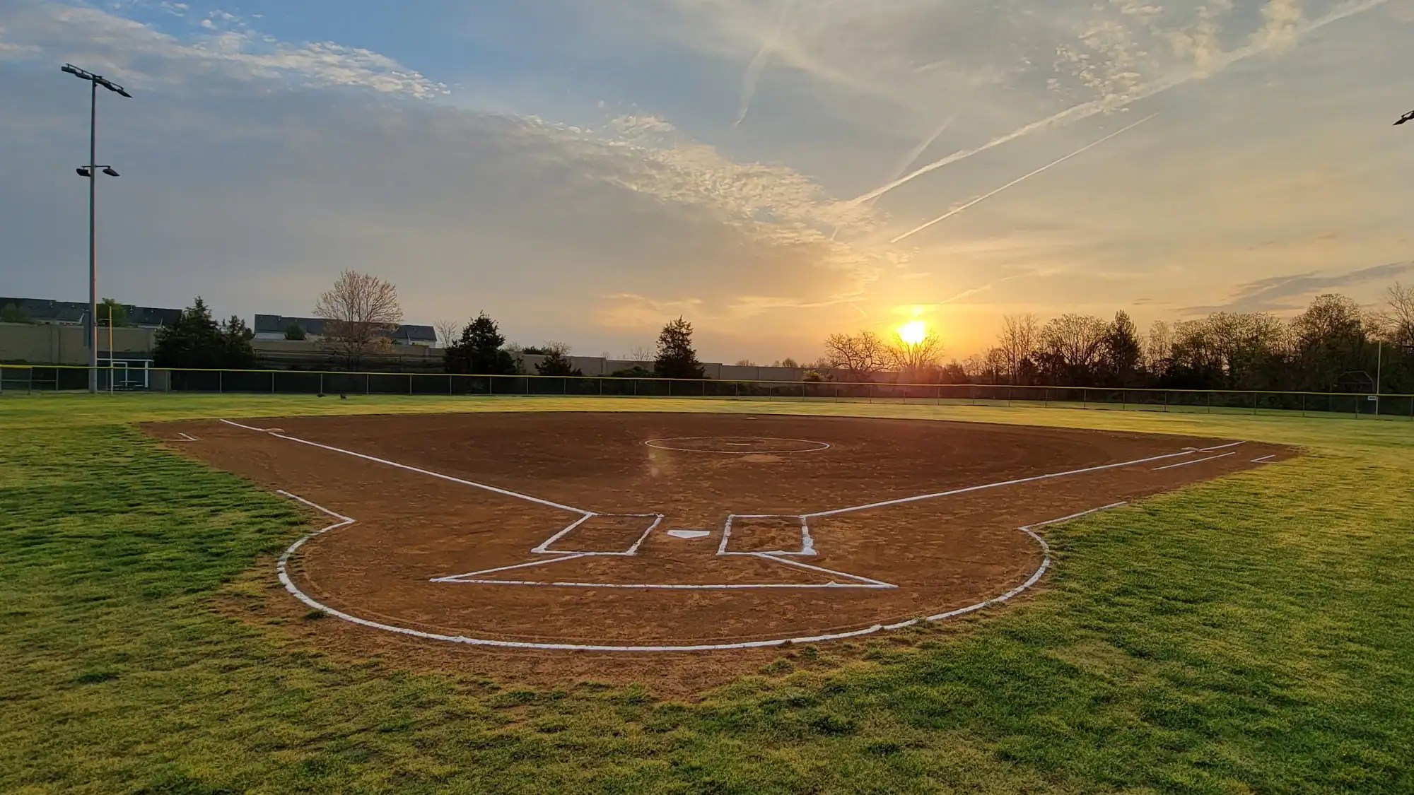 Youth baseball field at sunset, showing how a Cooperstown bucket list revolves around time at the fields during tournament week
