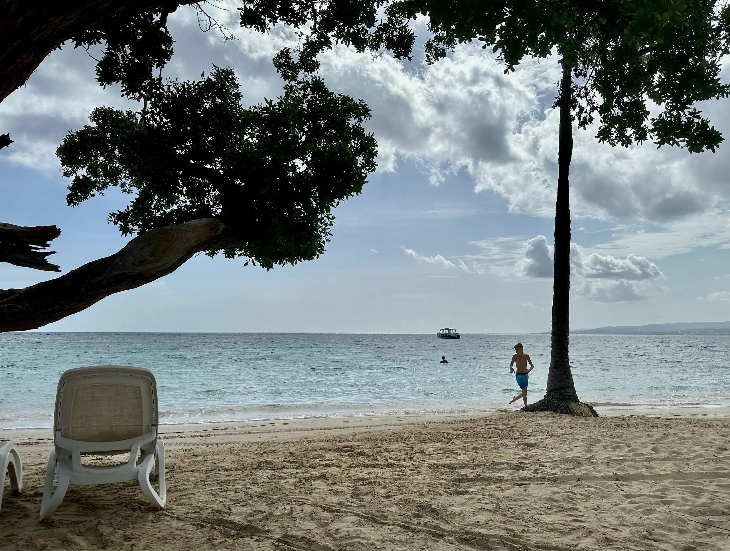 parent relaxing on a calm beach while kids play during a family all-inclusive vacation