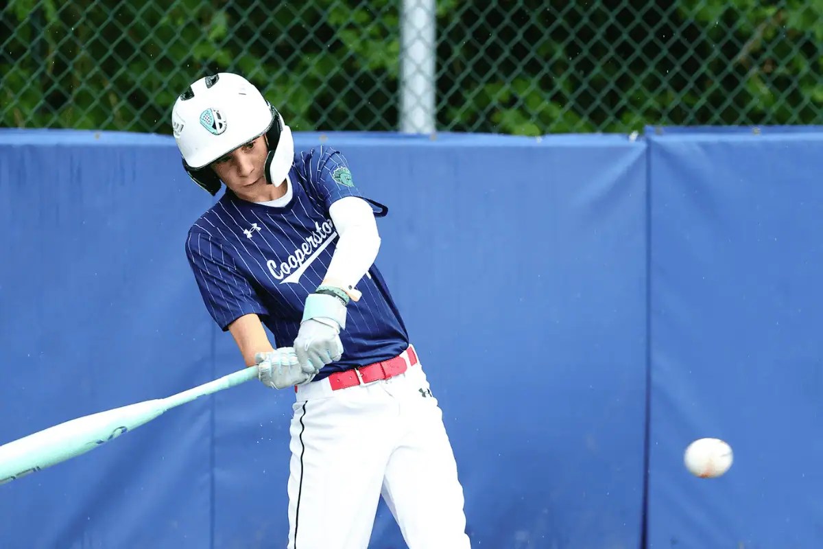 Professional action photo from the Cooperstown All Star Village photo package showing a youth baseball player batting during tournament play.