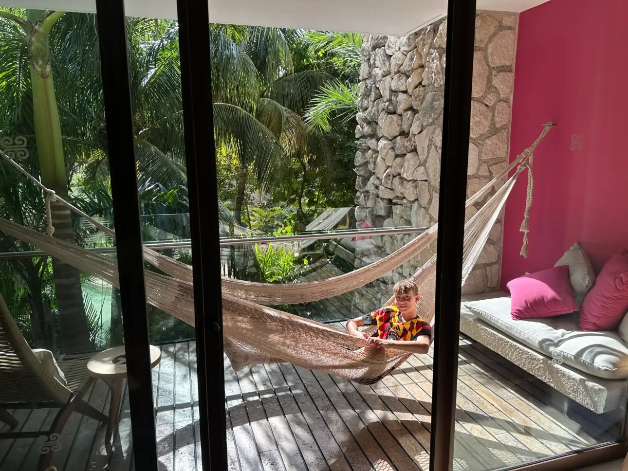 Teen relaxing in the balcony hammock of our Viento Building 2 room at Hotel Xcaret Mexico