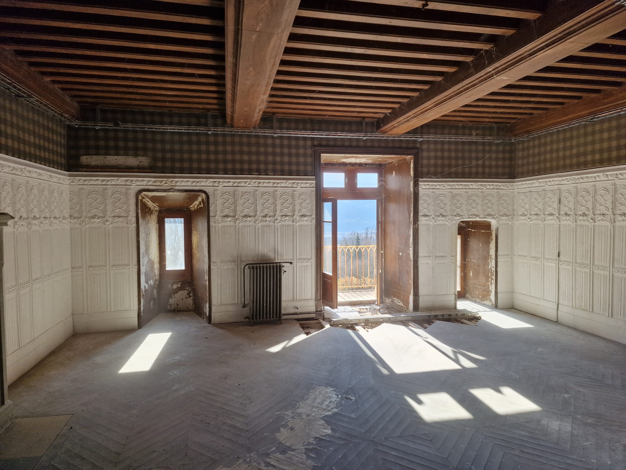 Salle du château avec panneaux blancs et plafond à solives