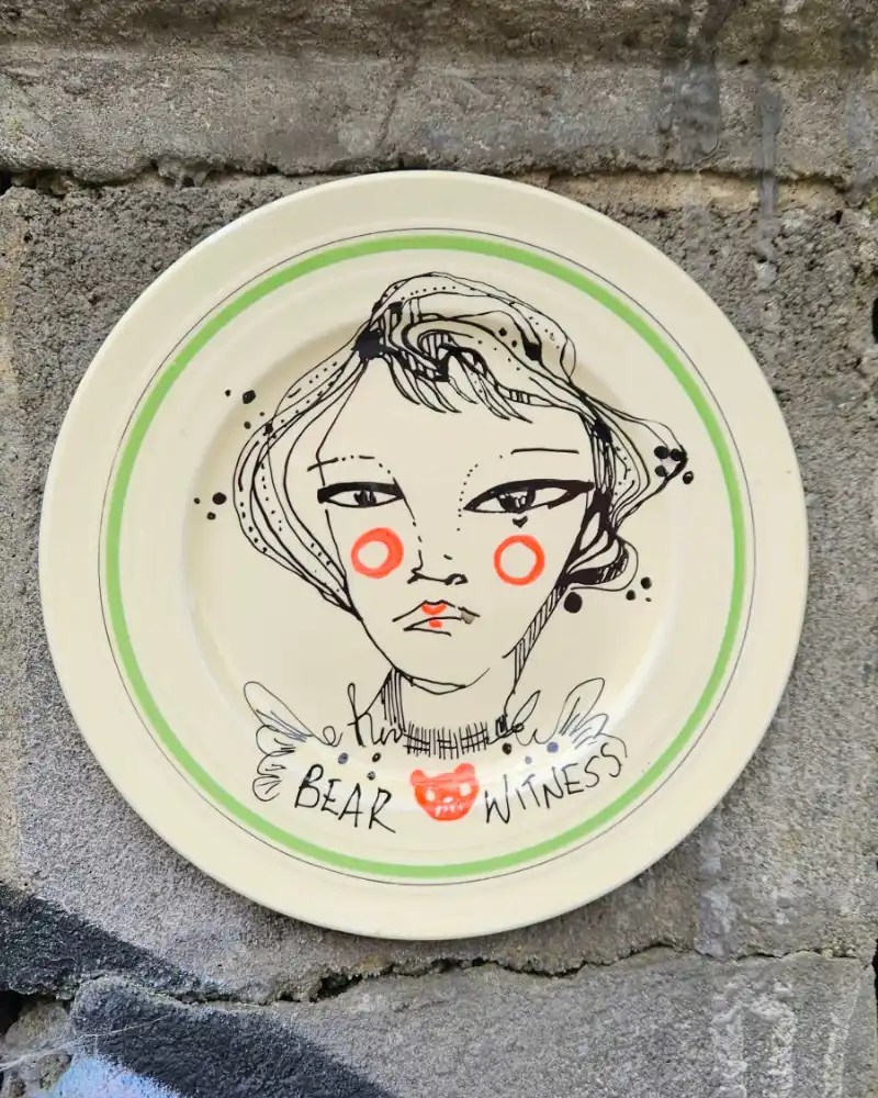 Hand-painted ceramic dish with a woman and with a green edge.