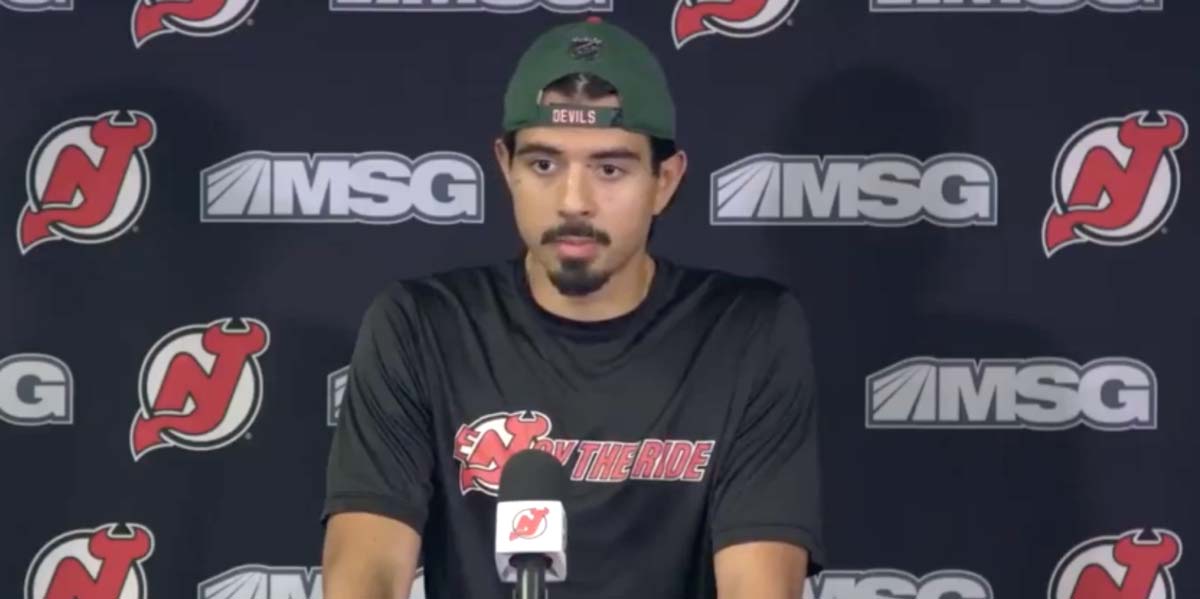 Jonas Siegenthaler gives a press conference with a New Jersey Devils background.