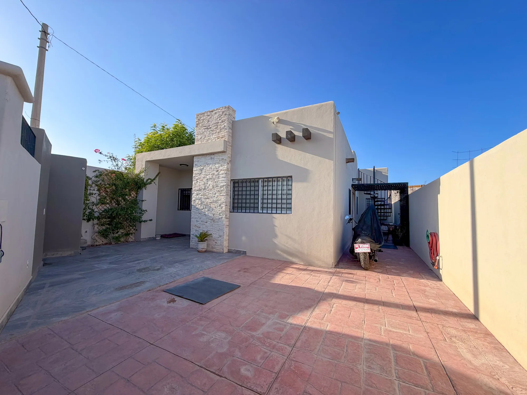 Patio trasero de Casa Xantus con chimenea de piedra laja y área techada