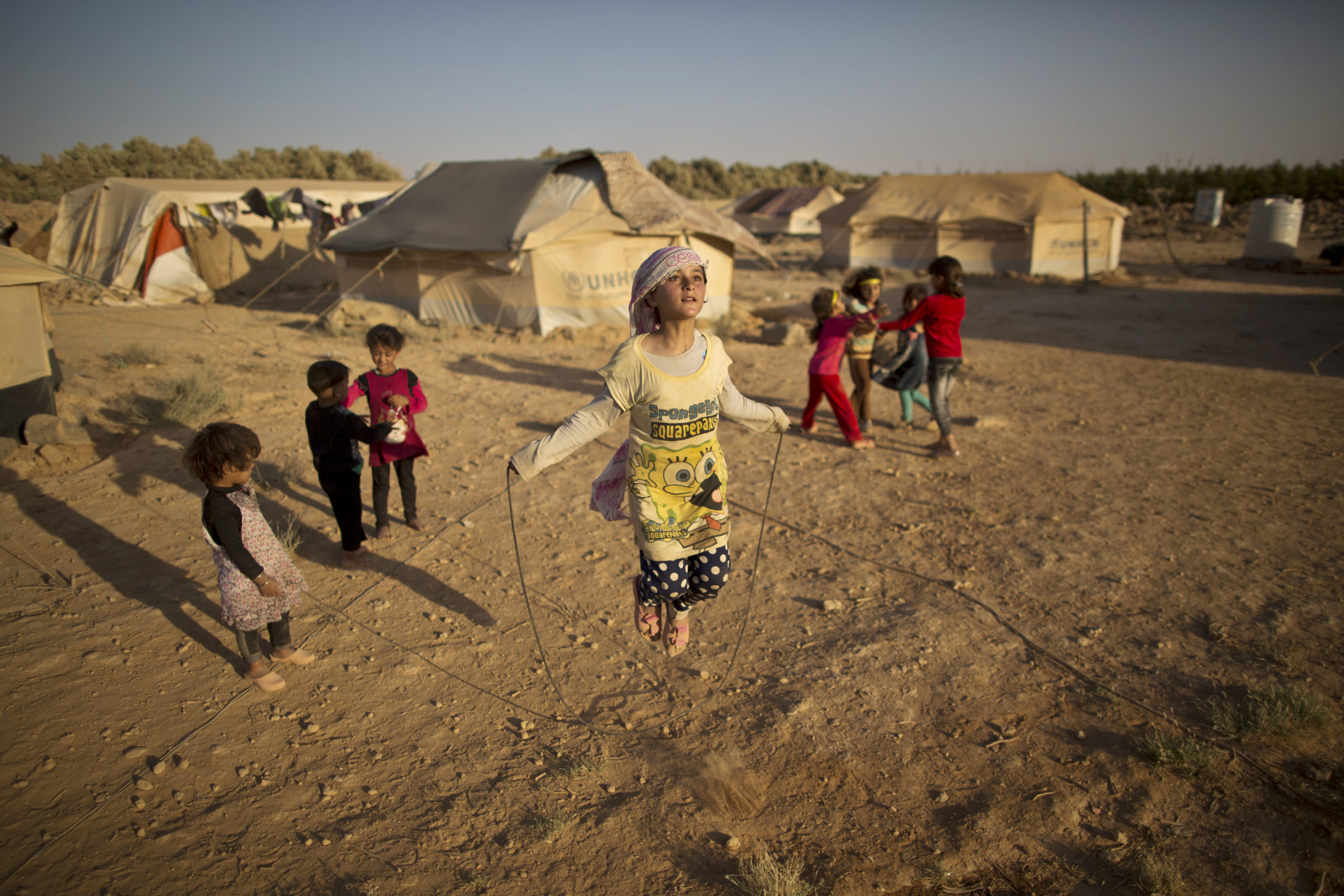 10-year-old Syrian refugee Zubaida Faisal, skips a rope while she and other children play near their tents at an informal tented settlement near the Syrian border on the outskirts of Mafraq, Jordan.