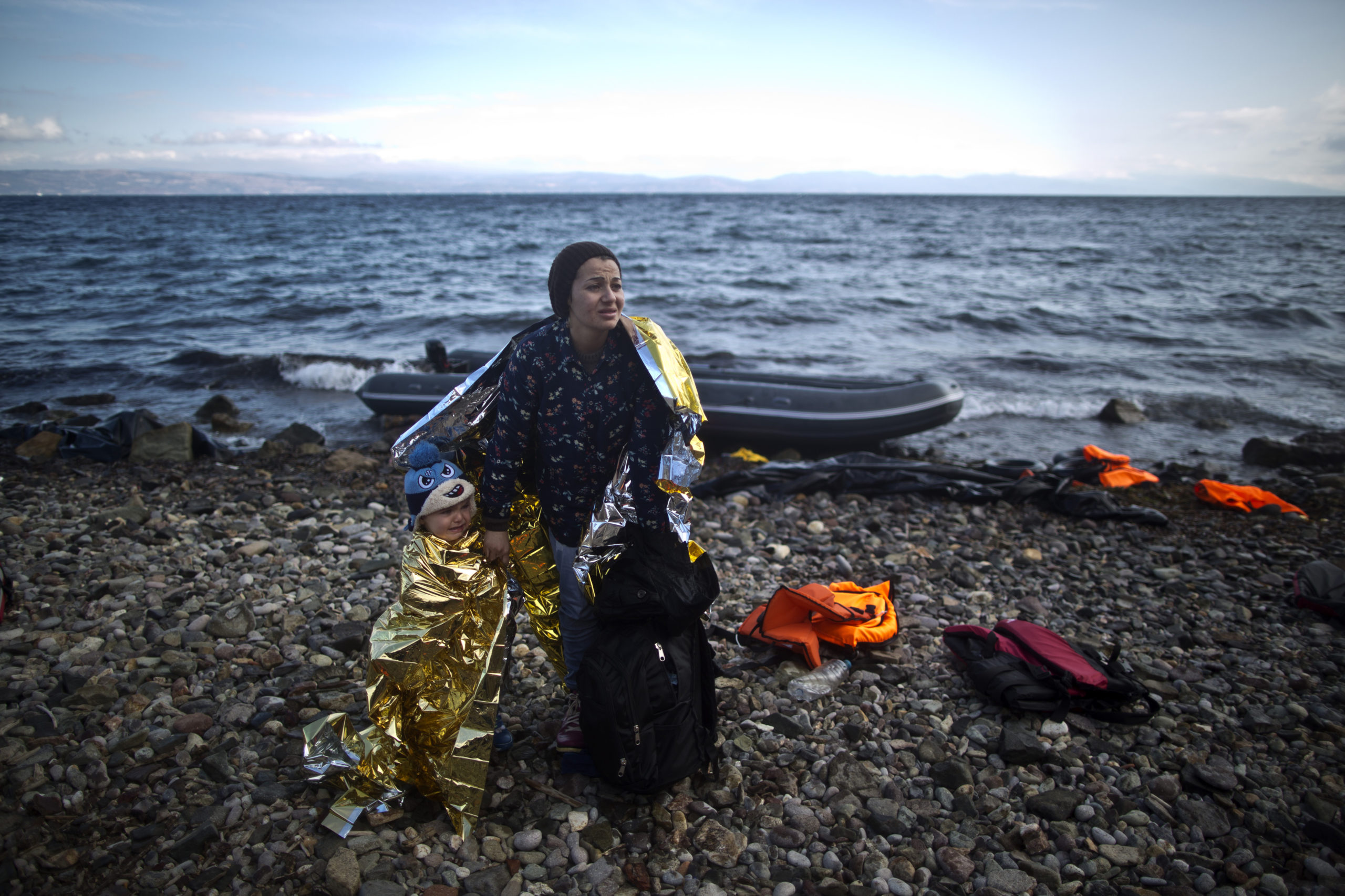A Syrian refugee woman and child are wrapped with thermal blankets to shelter from the cold after arriving on a dinghy from the Turkish coast to the northeastern Greek island of Lesbos, October 2015.