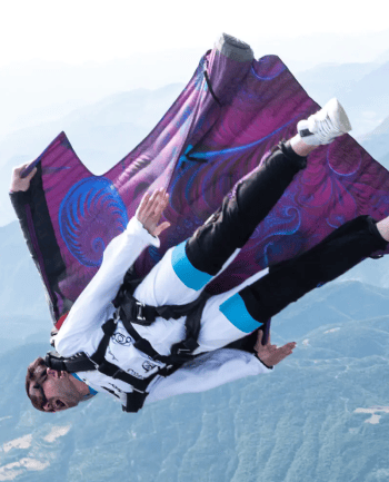 Deux personnes volent en wingsuit tandem au dessus de destinations de rêve.