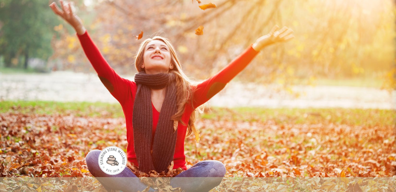 Woman sitting in a park throwing leaves