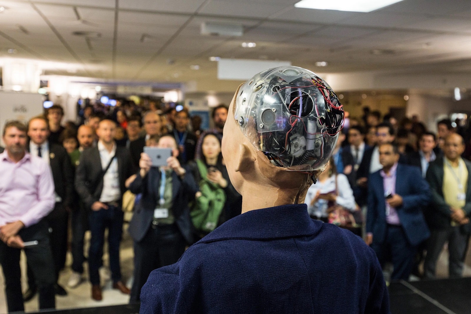 Sophia, an AI-powered humanoid robot, viewed from behind with exposed wiring and machinery in her head at the AI for Good Global Summit.