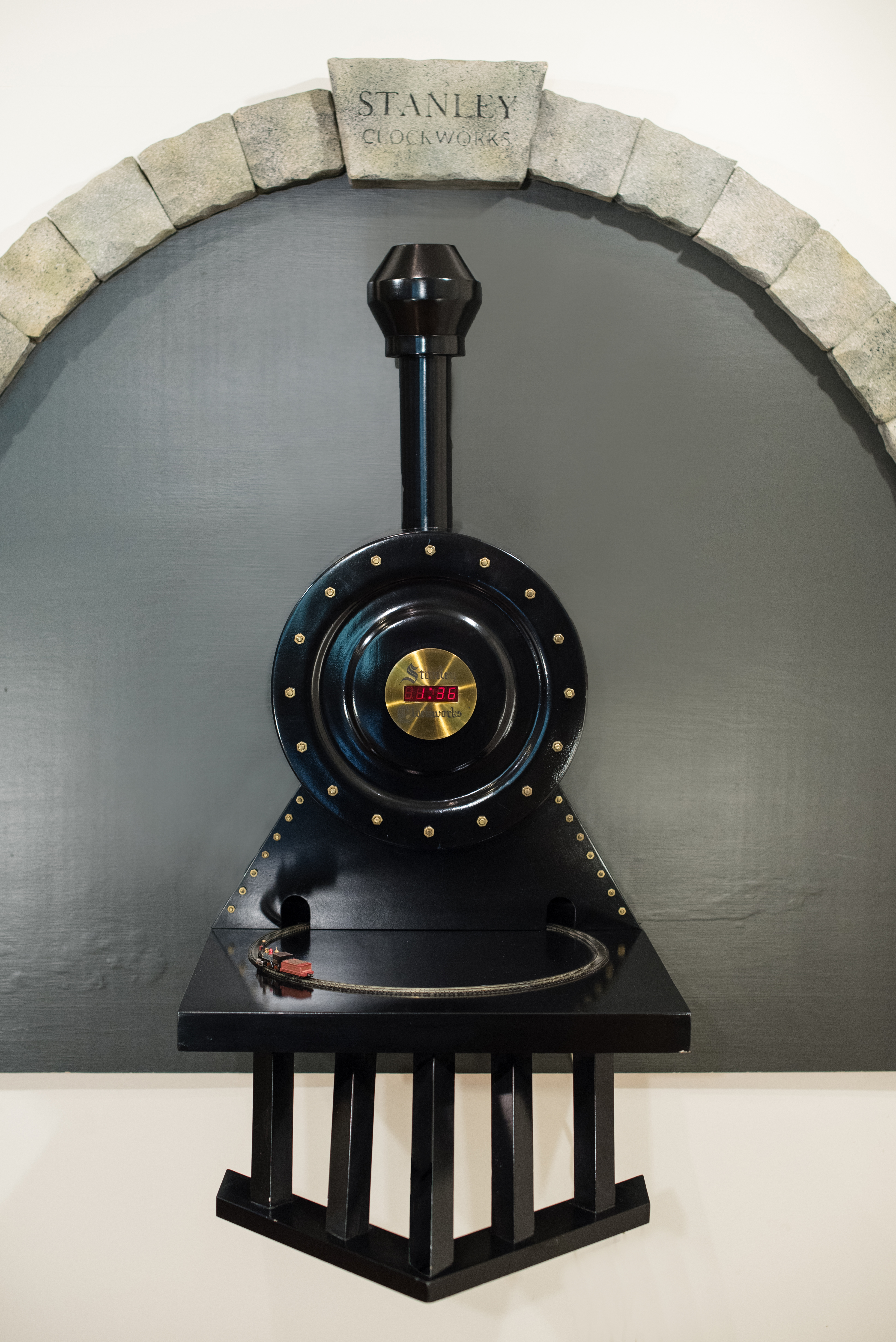 Clock made to look like the front of a train, with a small train and track circling in front.
